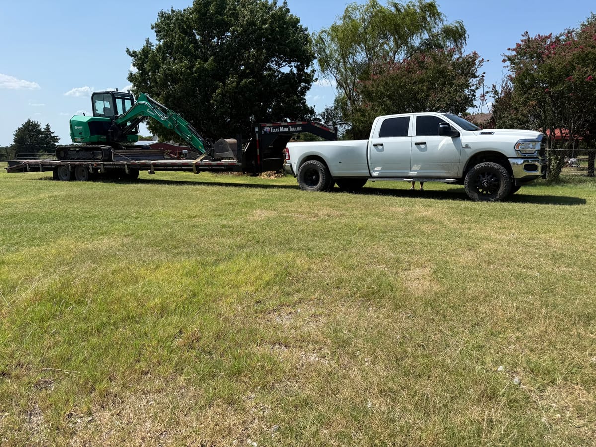 Kickin K Services RAM work truck hauling a mini excavator to a job site in North Texas